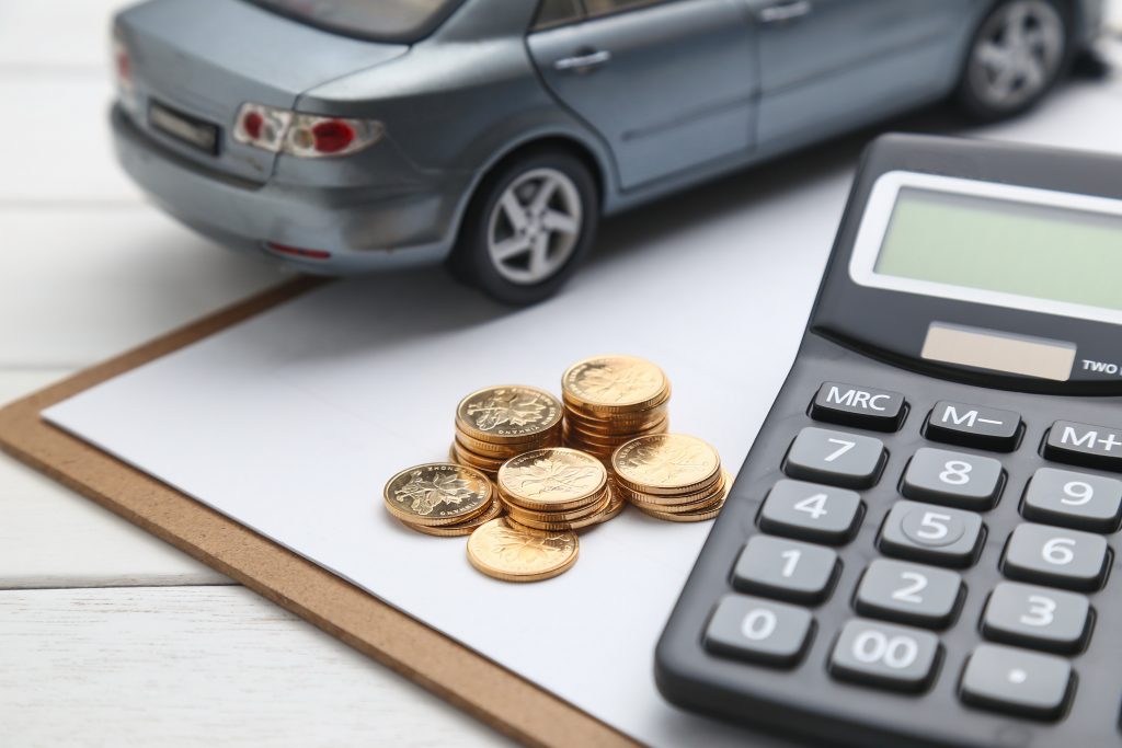 Model car next to a calculator and coins