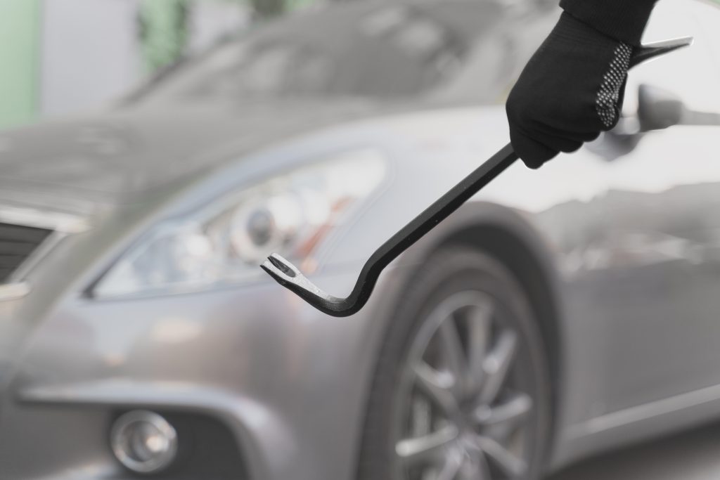 A thief trying to break into a car