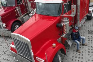 Man starting a career in the auto transport industry, sitting beside his truck.